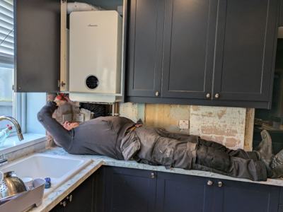 Engineer lying on kitchen worktop to install Worcester combi boiler